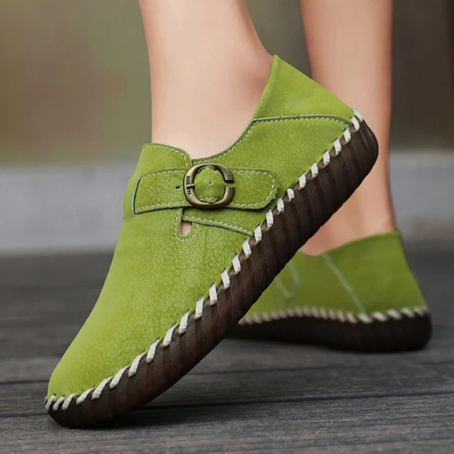 Green shoes with a buckle detail worn by a person on a blurred background